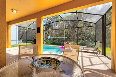 a glass house with a table and a swimming pool at Spacious 6BR family villa, 10 min to Disney, private pool, resort waterpark in Kissimmee