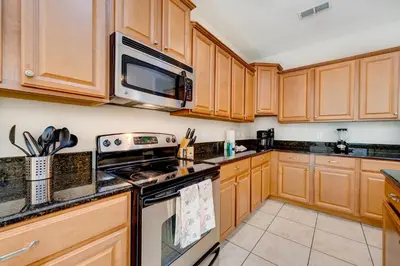 a kitchen with wooden cabinets and a stove top oven at Spacious 6BR family villa, 10 min to Disney, private pool, resort waterpark in Kissimmee