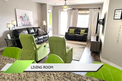 a living room with green chairs and a couch at Marvel-Themed, Spacious Condo Near OCCC, Sea World, Disney, and Universal with Extra Amenities in Orlando