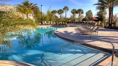 a large swimming pool with chairs and palm trees at Marvel-Themed, Spacious Condo Near OCCC, Sea World, Disney, and Universal with Extra Amenities in Orlando