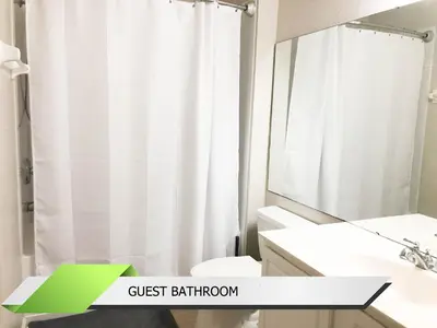 a bathroom with a white shower curtain and a sink at Marvel-Themed, Spacious Condo Near OCCC, Sea World, Disney, and Universal with Extra Amenities in Orlando