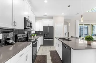 a large kitchen with white cabinets and black appliances at 5 Bedrroms 5 Bathrooms Storey Lake 2739 Bd in Kissimmee