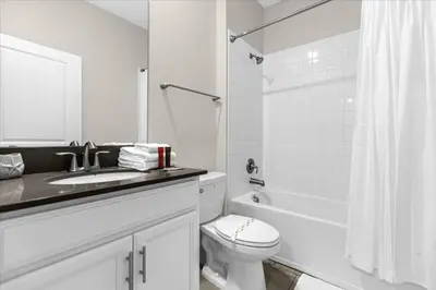a white bathroom with a toilet and a sink and a tub at 5 Bedrroms 5 Bathrooms Storey Lake 2739 Bd in Kissimmee