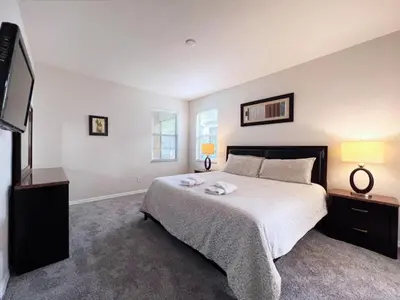 a bedroom with a bed and a flat screen tv at Luxurious 6Bd Pool Haven Refreshing and Chic-4464N home in Kissimmee