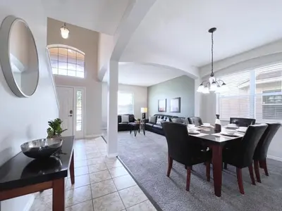 a dining room and living room with a table and chairs at Luxurious 6Bd Pool Haven Refreshing and Chic-4464N home in Kissimmee