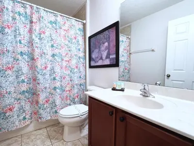 a bathroom with a toilet and a sink and a shower curtain at Luxurious 6Bd Pool Haven Refreshing and Chic-4464N home in Kissimmee
