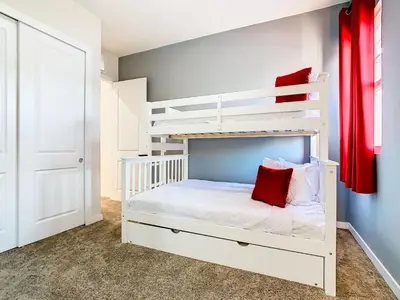 a bedroom with a white bunk bed with red pillows at Fabulous Paradise 3BR Townhouse near Disney and outlets in Orlando