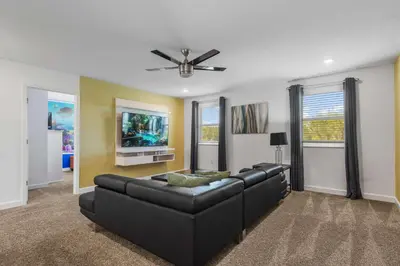 a living room with a black leather couch and a tv at Lake View Cozy Home w/ Pool & Games Near Disney in Kissimmee