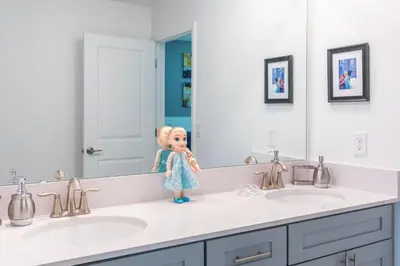a doll sitting on top of two sinks in a bathroom at Magical 10-Bedroom Disney Getaway Awaits! in Kissimmee