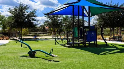 a park with a playground with an umbrella and a swing set at Luxury 12BR Villa w/ Pool & Spa Near Disney in Kissimmee