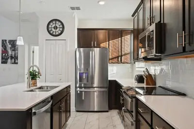a kitchen with a refrigerator and a clock on the wall at Luxurious Resort Home Near Disney & Shopping! in Kissimmee