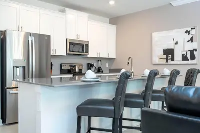 a kitchen with a counter with chairs and a refrigerator at Fantastic Mickey house Waterpark near Disney 2572 in Kissimmee