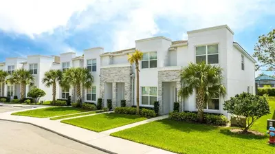 a white house with palm trees in front of it at Comfortable home Near Disney & Private Pool 17414 in Orlando