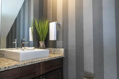 a bathroom with a white sink and a striped wall at Stunning Villa 5 min to Disney in Orlando