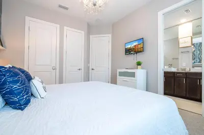 a bedroom with a large white bed and a bathroom at Stunning Villa 5 min to Disney in Orlando