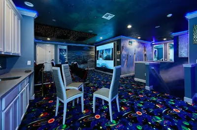 a room with a bar with chairs and a video game at Remarkable Mansion Sleep 36 Cinema-Bowling Alley & More in Kissimmee