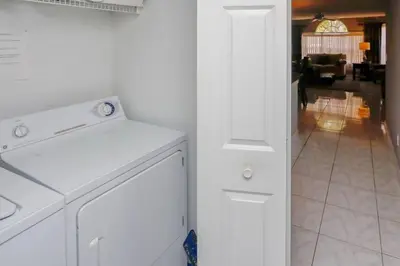 a white kitchen with a dishwasher and a living room at HARRY POTTER LIVES HERE! Unforgettable Home, Pool, Sleeps 8, Near Dis, LOW Rates! in Kissimmee