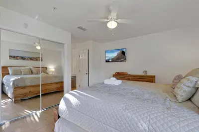 a white bedroom with a bed and a ceiling fan at Spacious Condo W/ Pool,Gym near Disney & Seaworld in Kissimmee
