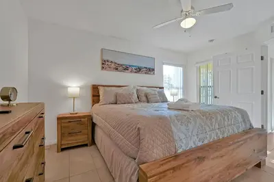 a bedroom with a bed with a dresser and a ceiling fan at Spacious Condo W/ Pool,Gym near Disney & Seaworld in Kissimmee