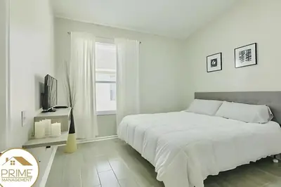 a white bedroom with a bed and a window at Renewed & Cozy 4BD Great Location near Disney in Kissimmee