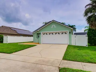 a house with a white and green garage at Pool home 5 miles to Disney Great for families in Orlando
