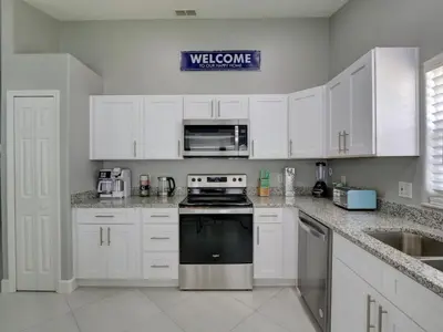 a kitchen with white cabinets and a black stove top oven at Pool home 5 miles to Disney Great for families in Orlando