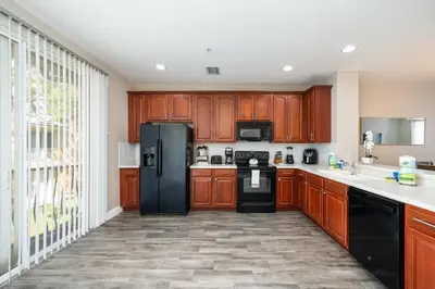a kitchen with wooden cabinets and a black refrigerator at Beautiful Family Townhome, Near The Parks - 8000-104 in Orlando