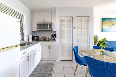 a kitchen with white cabinets and a table with blue chairs at Charming Lakeview Retreat I in Orlando