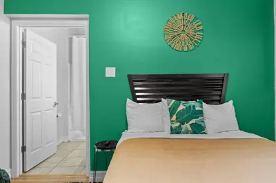 a green bedroom with a bed and a clock on the wall at Banana Leaf Villa-Island Groove-Standard Suite in Orlando