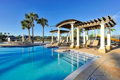 a swimming pool with chairs and a pergola at Windsor Hills Townhouse in Orlando