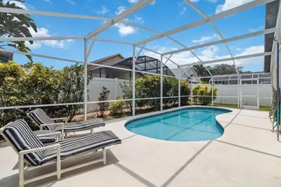 a patio with two chairs and a swimming pool at Indian Ridge- 4 bedroom home with Game Room in Orlando