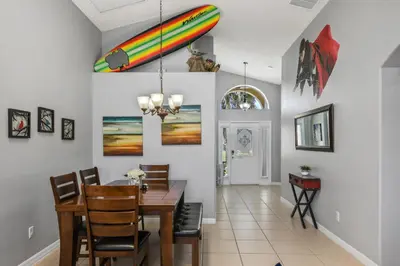 a dining room with a table and a surfboard on the wall at Wheelchair accessible Lakeview 4BR house with pool spa themed rooms game room in Kissimmee