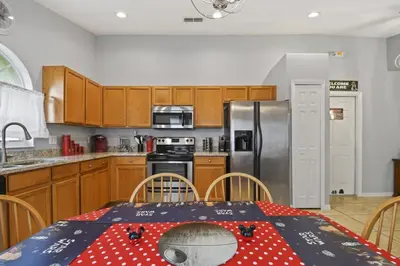 a kitchen with a table and a refrigerator at Themed 4BR house pool game room 10 min Disney in Orlando
