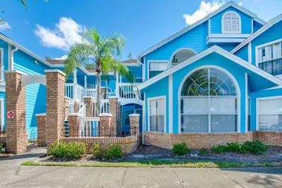 a blue house with a palm tree in front of it at Disney's Townhome in Kissimmee