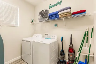 a laundry room with a washing machine and a shelf at Dream Getaway Modern 6-Bedroom Vacation Home in Kissimmee