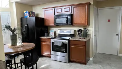 a kitchen with a stove and a table and a microwave at Excelente Casa Vacacional in Kissimmee