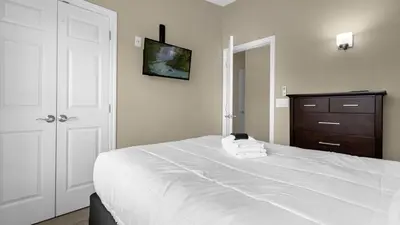 a bedroom with a large white bed and a dresser at Sunny Stay in FL - 4-Bedroom Townhome by Disney! in Orlando