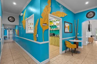 a hallway with a blue wall with leaves on it at Banana Leaf Villa-Vintage Vibes Suites in Orlando