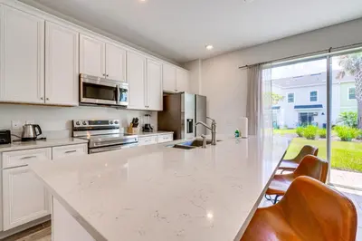 a kitchen with white cabinets and a large marble counter top at about 11 Mi to Disney Bright Kissimmee Townhome! in Orlando