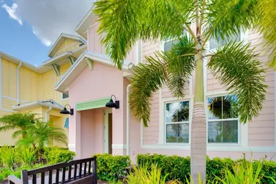 a house with a palm tree in front of it at about 11 Mi to Disney Bright Kissimmee Townhome! in Orlando