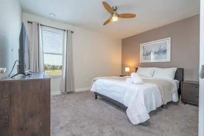 a bedroom with a bed and a ceiling fan at Premium 6BR home w/Pool-BBQ just 10min to Disney in Kissimmee