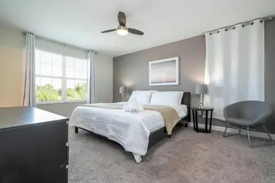 a bedroom with a bed with a ceiling fan and a chair at Premium 6BR home w/Pool-BBQ just 10min to Disney in Kissimmee