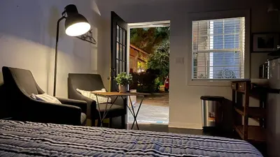 a bedroom with a bed and two chairs and a table at Lovely Spacious Guesthouse in Mills 50 District in Orlando