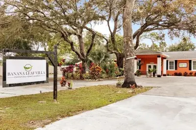 a sign in front of a building with trees at Banana Leaf Villa-Vintage Vibes- King Suite in Orlando
