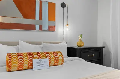 a bed with a yellow and orange pillow on it at Banana Leaf Villa-Vintage Vibes- King Suite in Orlando