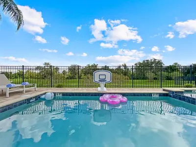 a swimming pool with a basketball hoop in front of a fence at Luxury 5BR Villa, Pool Spa, 15min Disney in Orlando