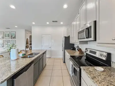 a kitchen with white cabinets and granite counter tops at Luxury 5BR Villa, Pool Spa, 15min Disney in Orlando