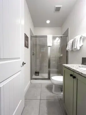 a white bathroom with a shower and a toilet at Luxury 5BR Villa, Pool Spa, 15min Disney in Orlando