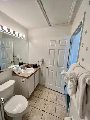 a bathroom with a toilet and a sink and a mirror at Grand Deluxe 3BR Townhouse near Disney Parks in Kissimmee