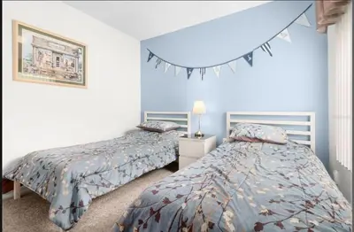 two beds in a bedroom with blue walls at Tropical Escape By Shine Villas 244 in Kissimmee